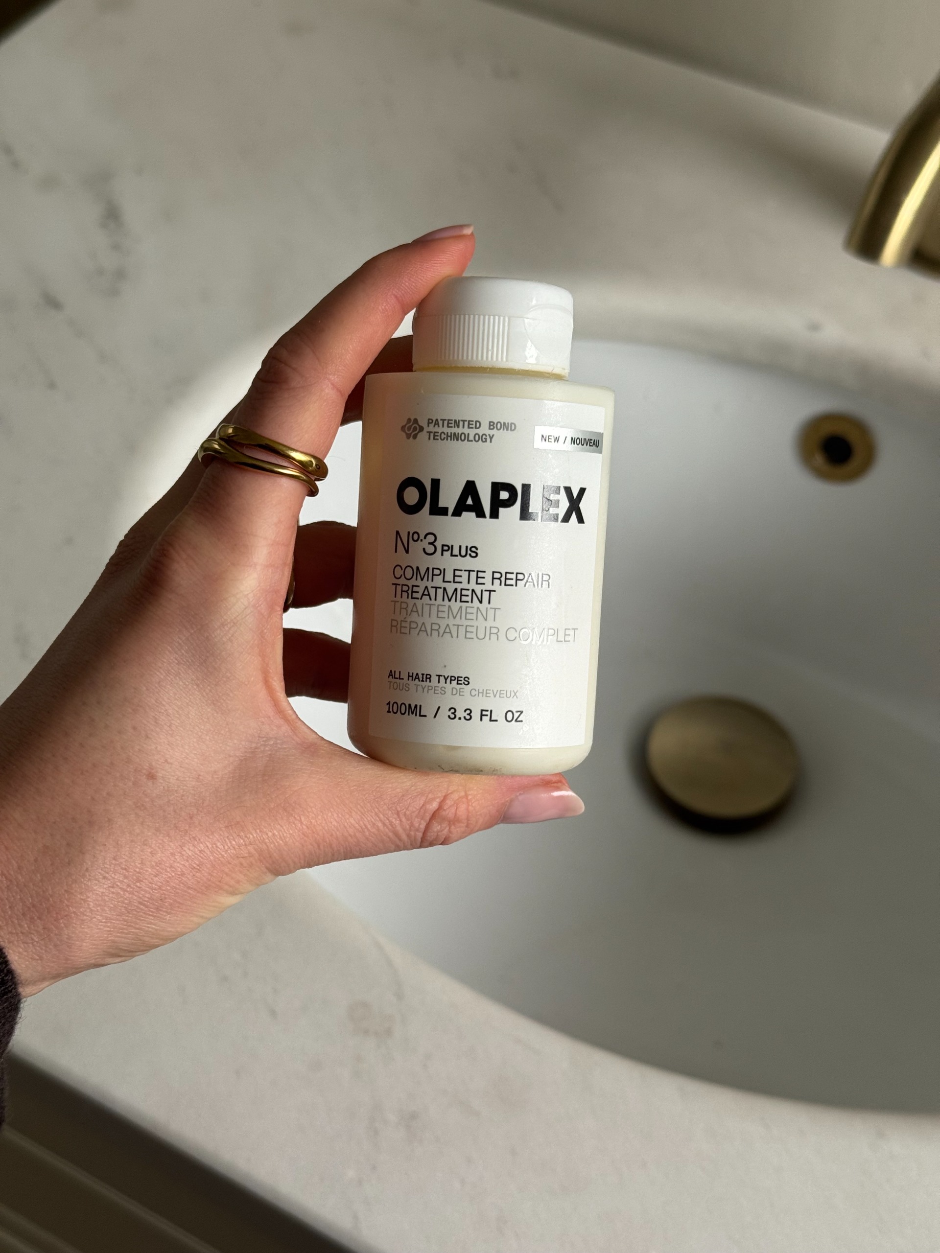 Eleanor holding a bottle of Olaplex no3 by the sink