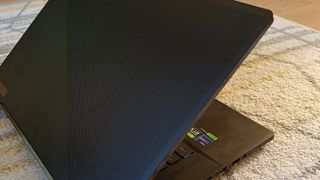 An ASUS ROG Zephyrus M16 gaming laptop sitting on a rug