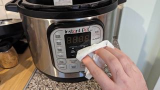 The control panel of an Instant Pot being wiped with a cloth