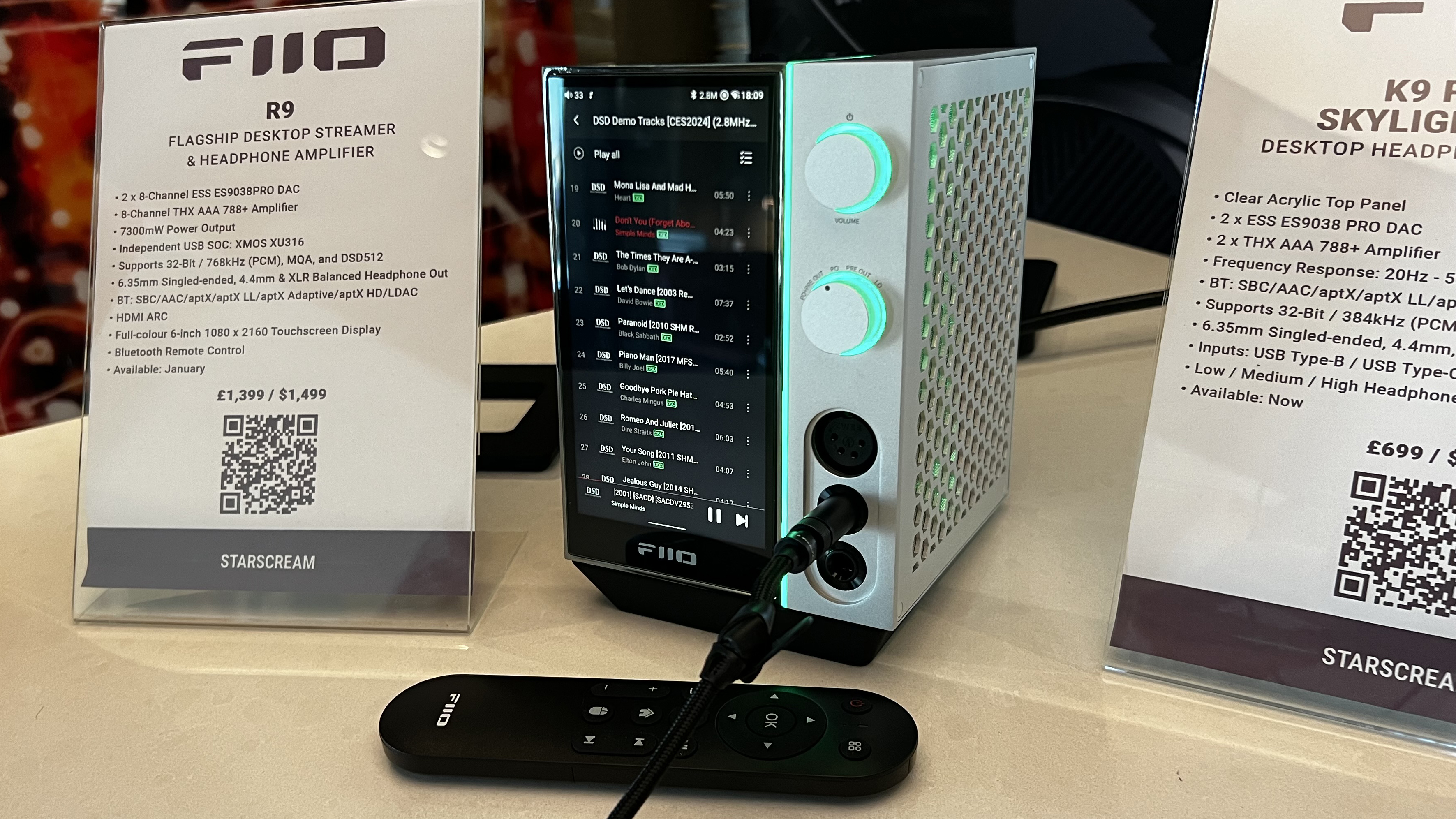 Fiio R9 music player on a wooden table next to a sign listing its features
