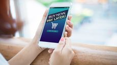 A woman's hands hold a phone that has the words "buy now, pay later" on the screen.