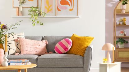 A small living room with a gray couch and colorful pillows and artwork