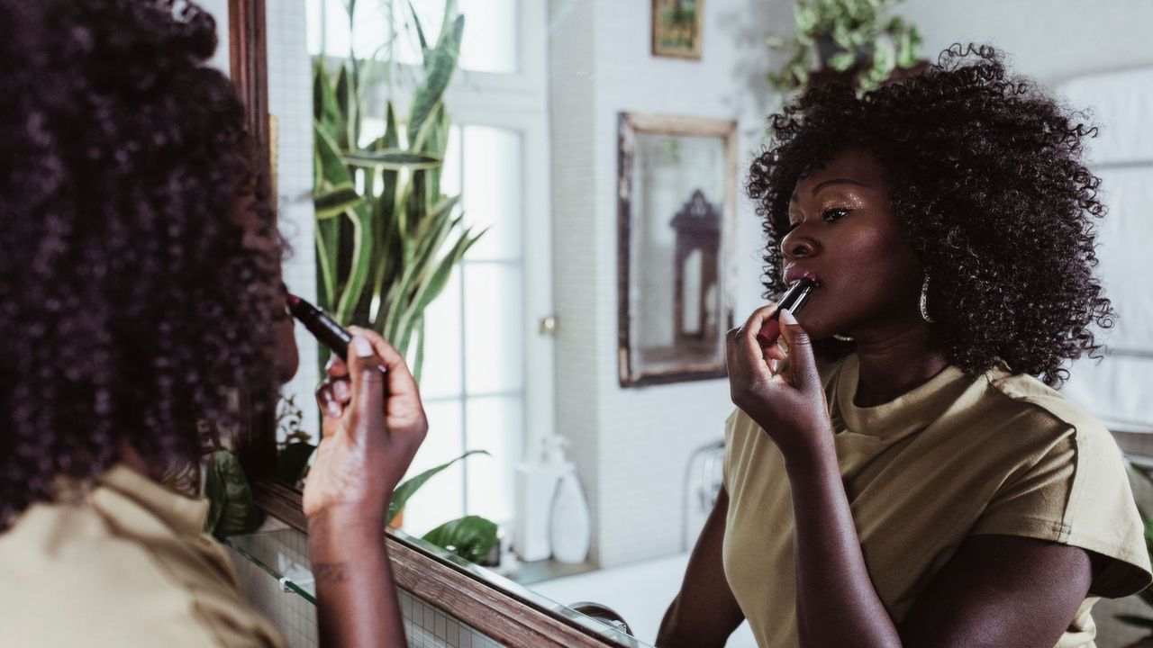 Best nude lipstick - woman applying lipstick in mirror