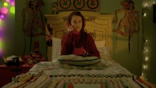 Madeleine Harris sitting up in bed while on the phone in Paddington 2.