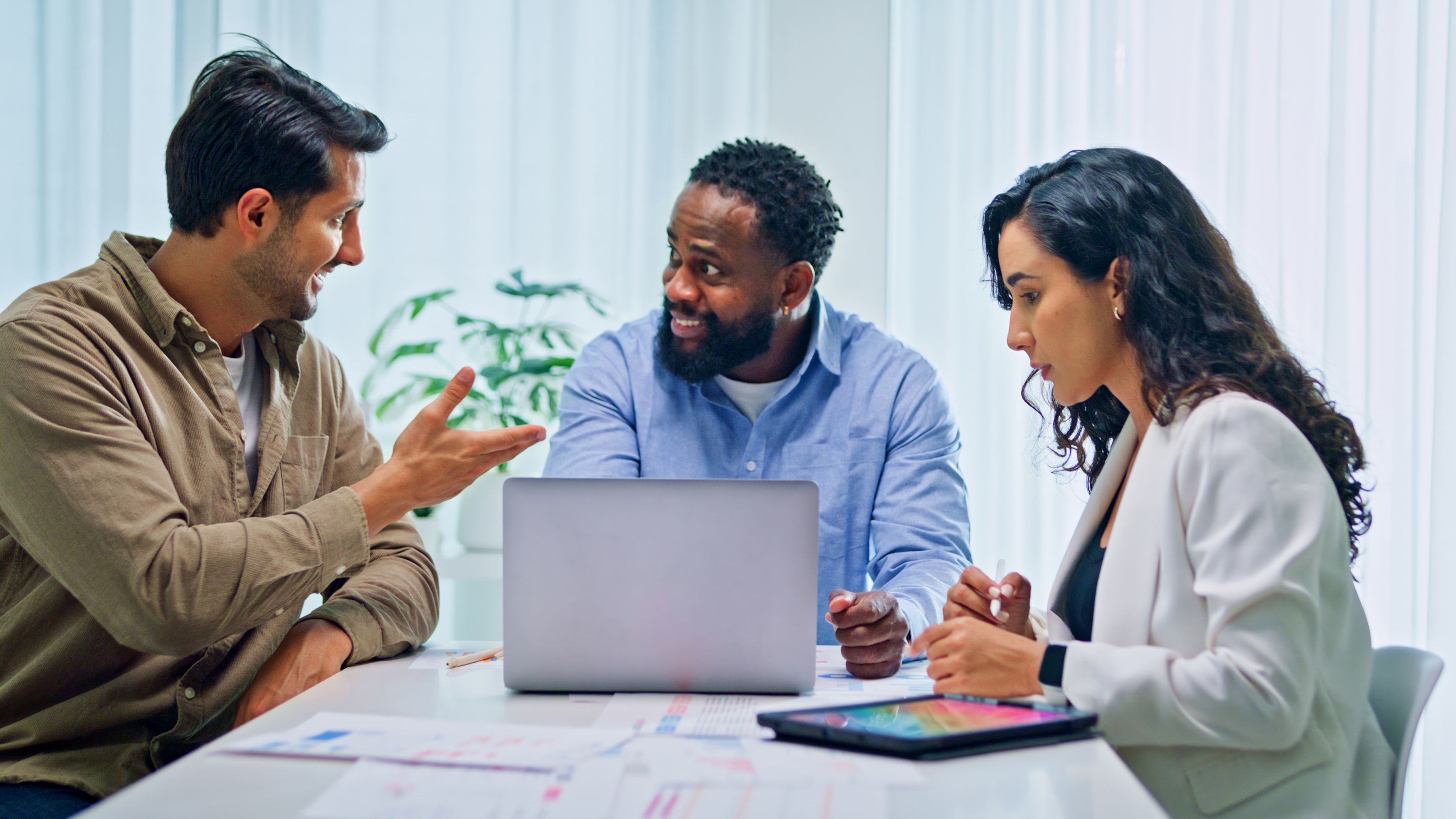 An adviser works with two clients at a conference room table in his office.