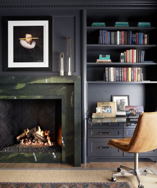 black home office with built-in shelving, tan swivel chair and fireplace