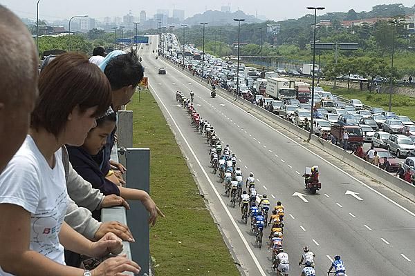 The peloton make their way towards Kuala Lumpur as traffic on the freeway going out is at a standstill.
