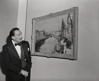 Salvador Dali looks at a painting