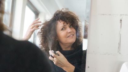 woman spraying hair with dry shampoo