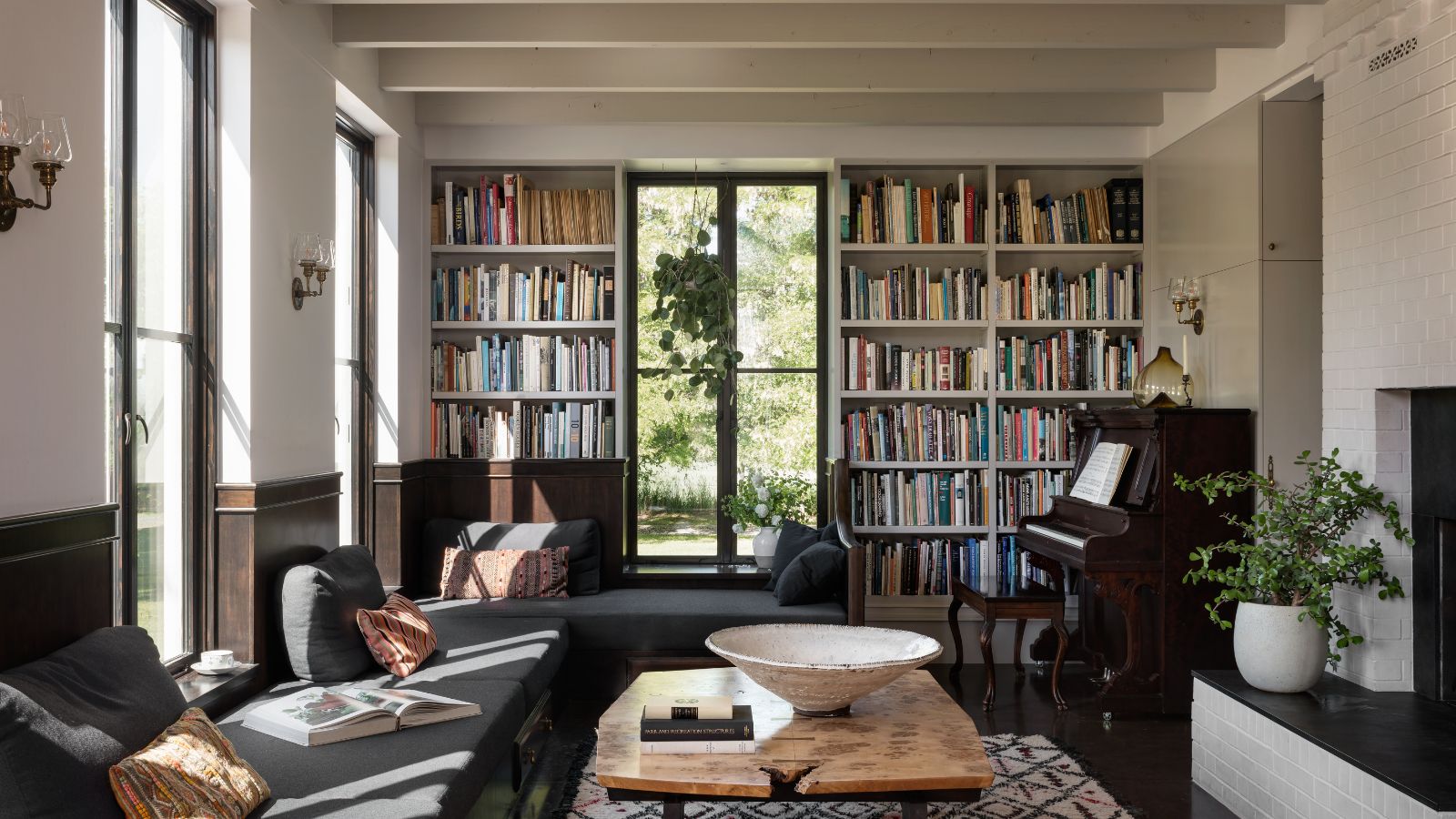 Living room with white beams, built-in bookshelves, sofa bench and wood coffee table