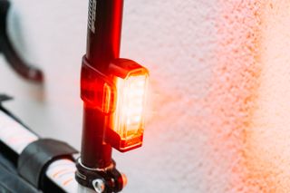 A red bike light attached to a seat post, lit up brightly