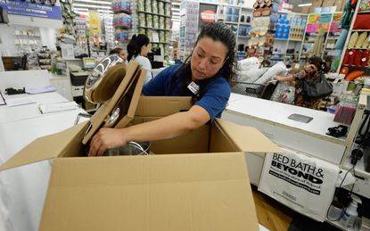 A store manager packs cookware at a Bed Bath & Beyond amid shoppers.