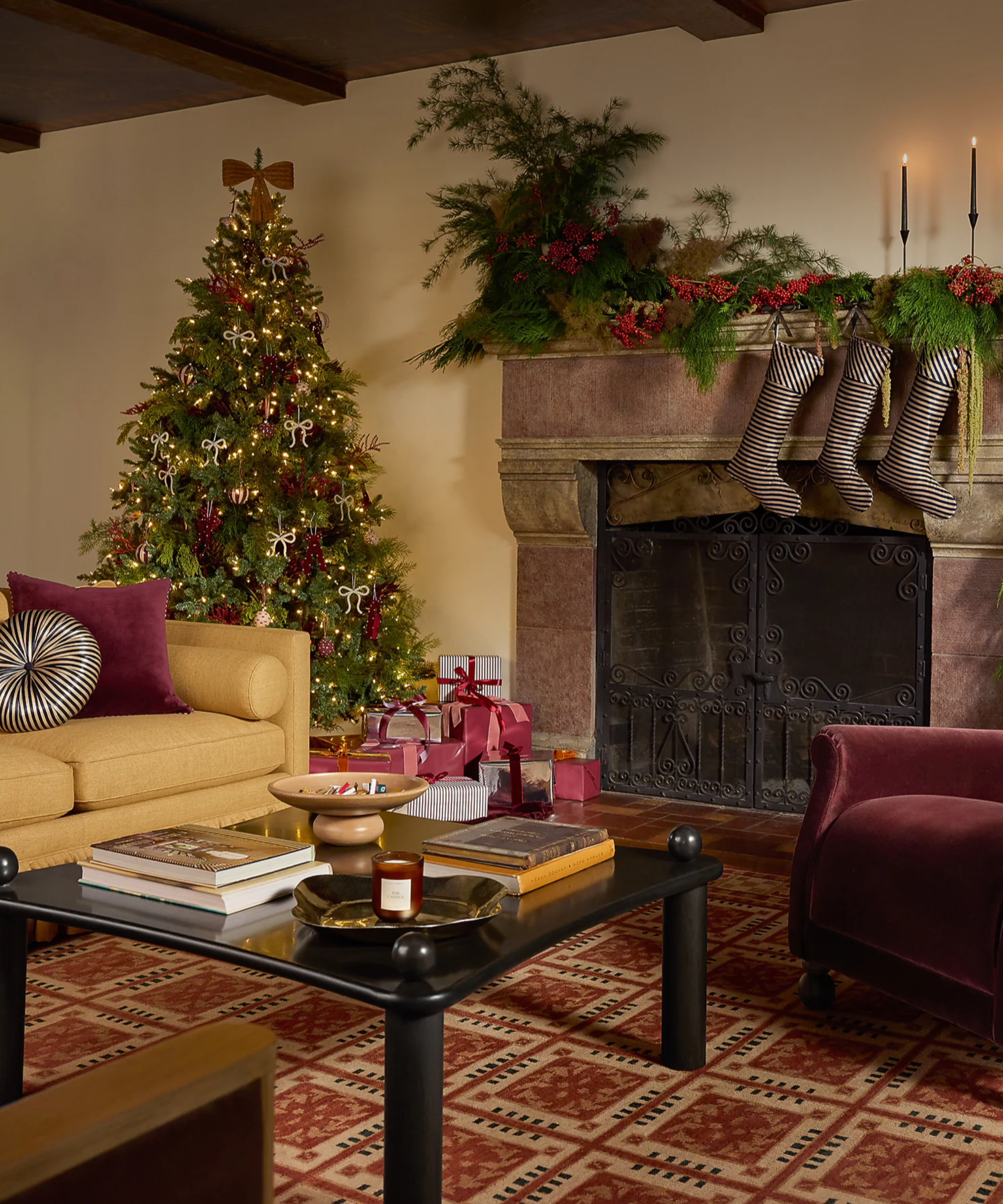 Stylish Christmas living room featuring a glowing tree dressed in velvet ribbon and pearl ornaments, a mustard sofa with striped circular cushions, and coordinating striped stocking along the mantel