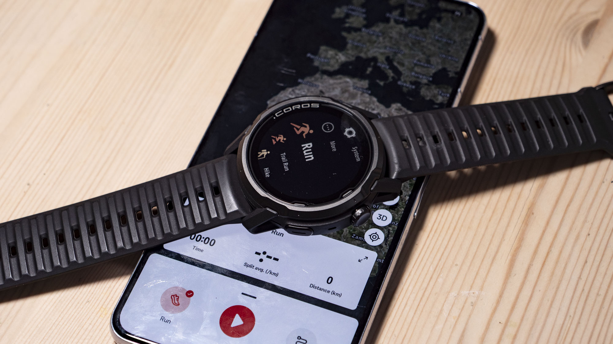 Coros Apex 4 running watch resting on top of a phone, with the Strava app UI