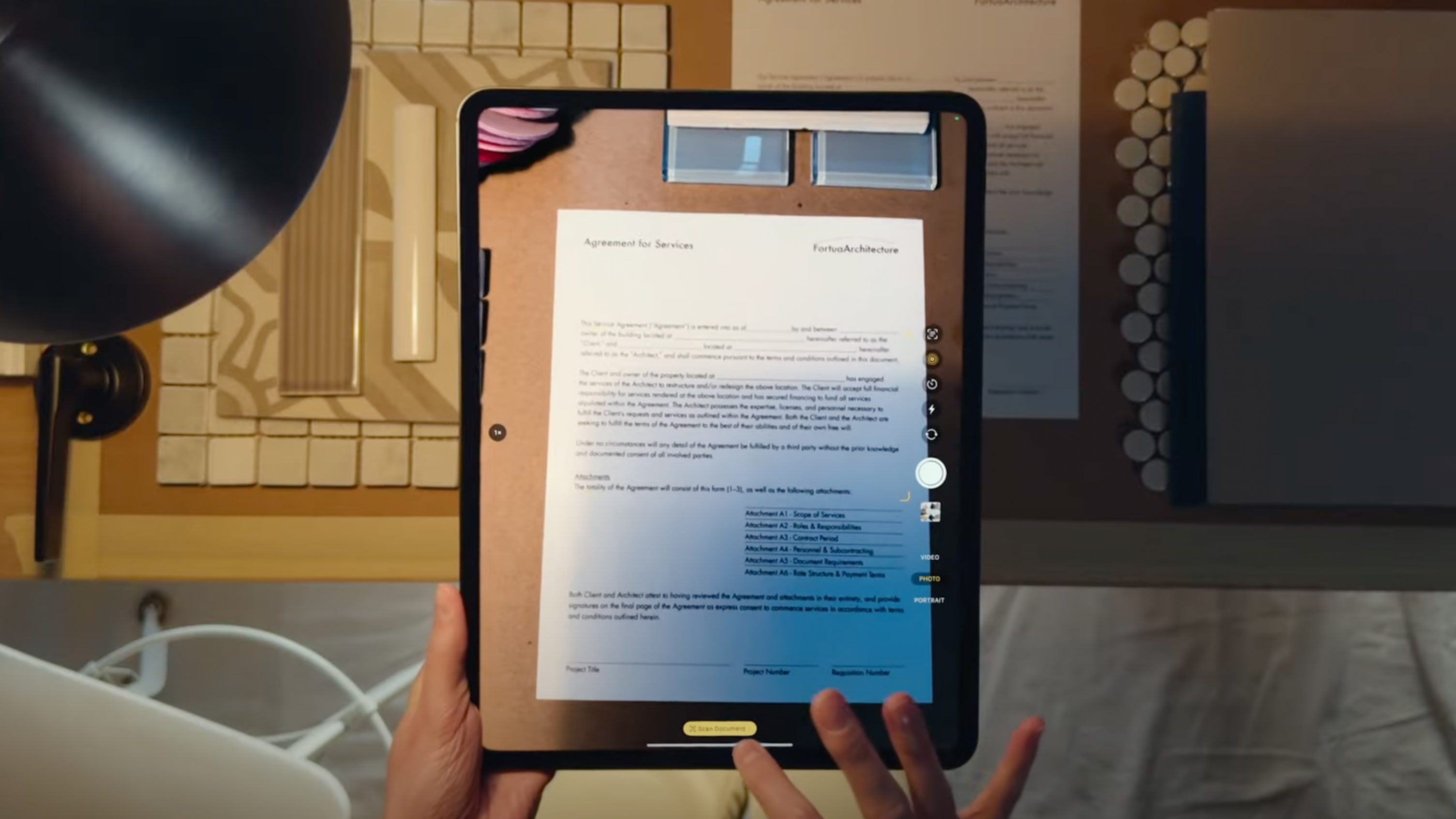 A hand holding an iPad that's scanning a document