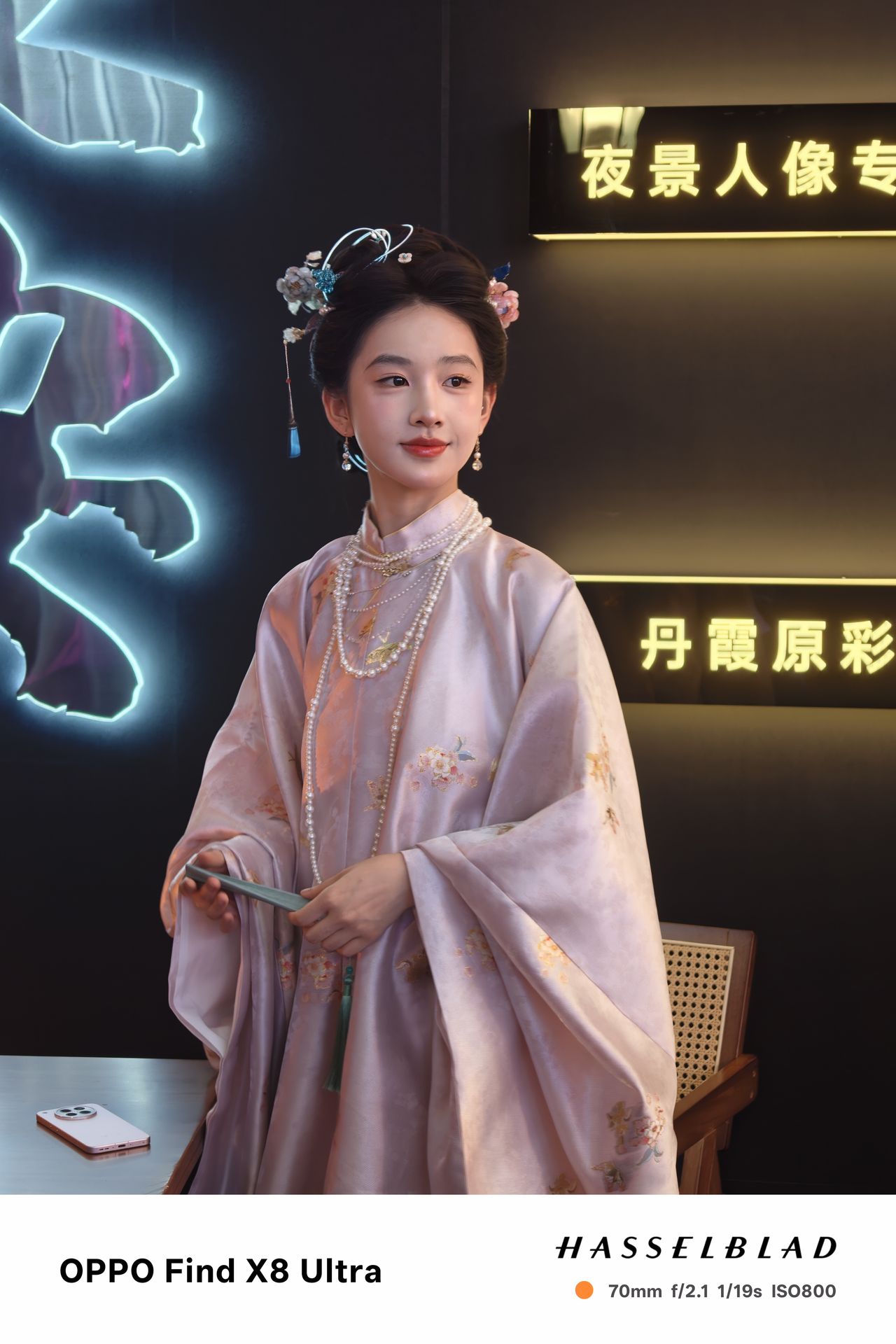 A person in traditional Chinese dress in front of neon signs
