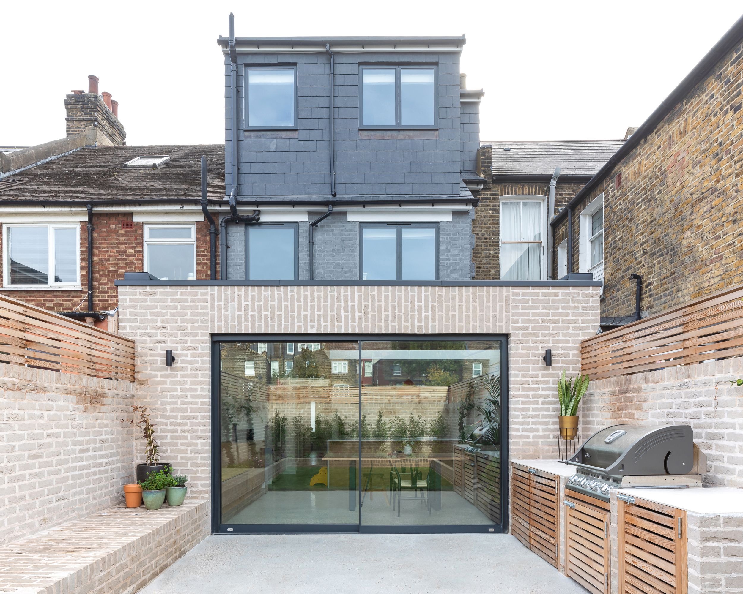 Bagudvidelse af Neighbourhood Studio Architects, der fører ud til en terrasse med et udekøkken