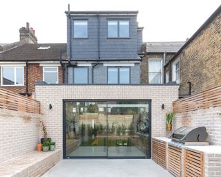 Rear extension by Neighbourhood Studio Architects leading out to a terrace with an outdoor kitchen