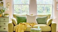 Things people with clean small homes have in common are good to know. Here is a green living area with lime green and beige walls, two windows with folded blinds, a lime green couch with throw pillows, an abstract light green coffee table in front of it, and distressed vintage green drawers behind it