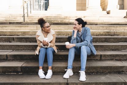 two women sitting on steps while talking