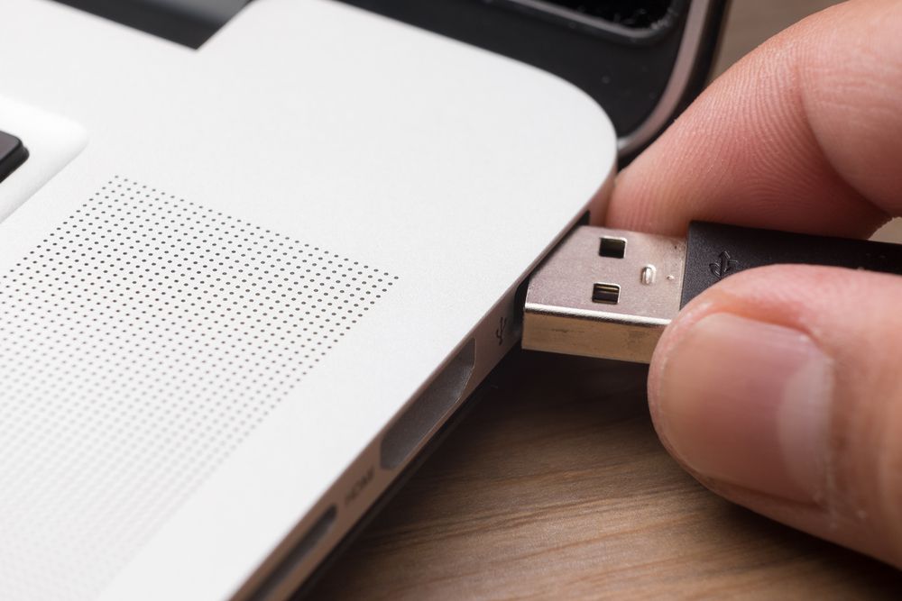 Image of a worker inserting or removing a USB drive from a laptop