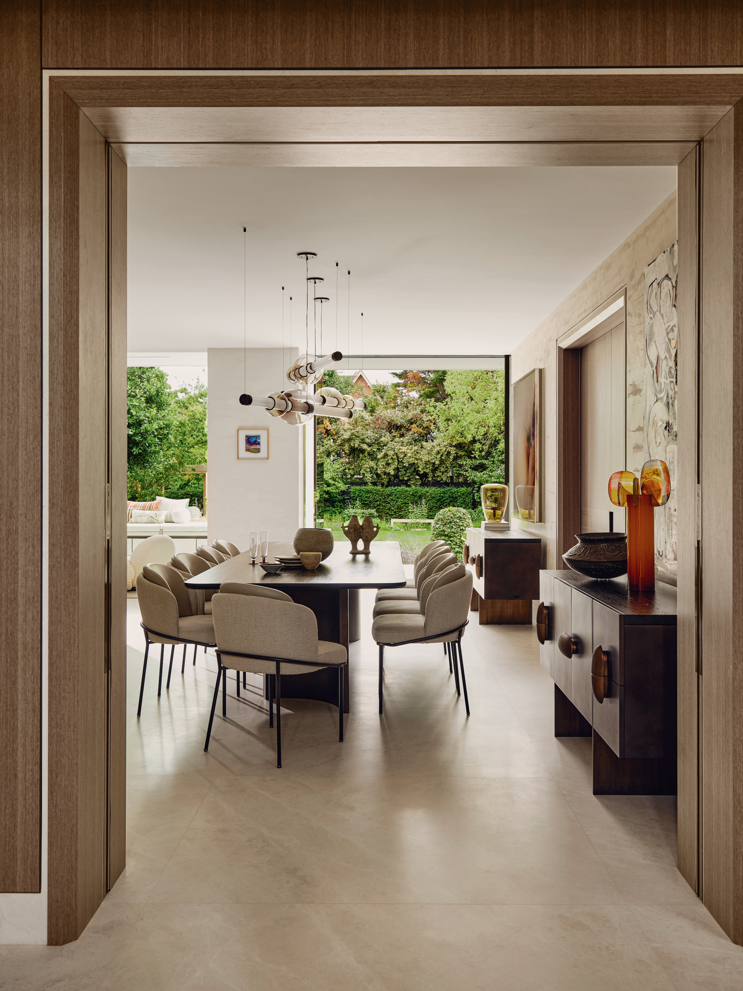 View into kitchen-diner with cream walls, cream dining chairs and dark wood dining table and sideboards