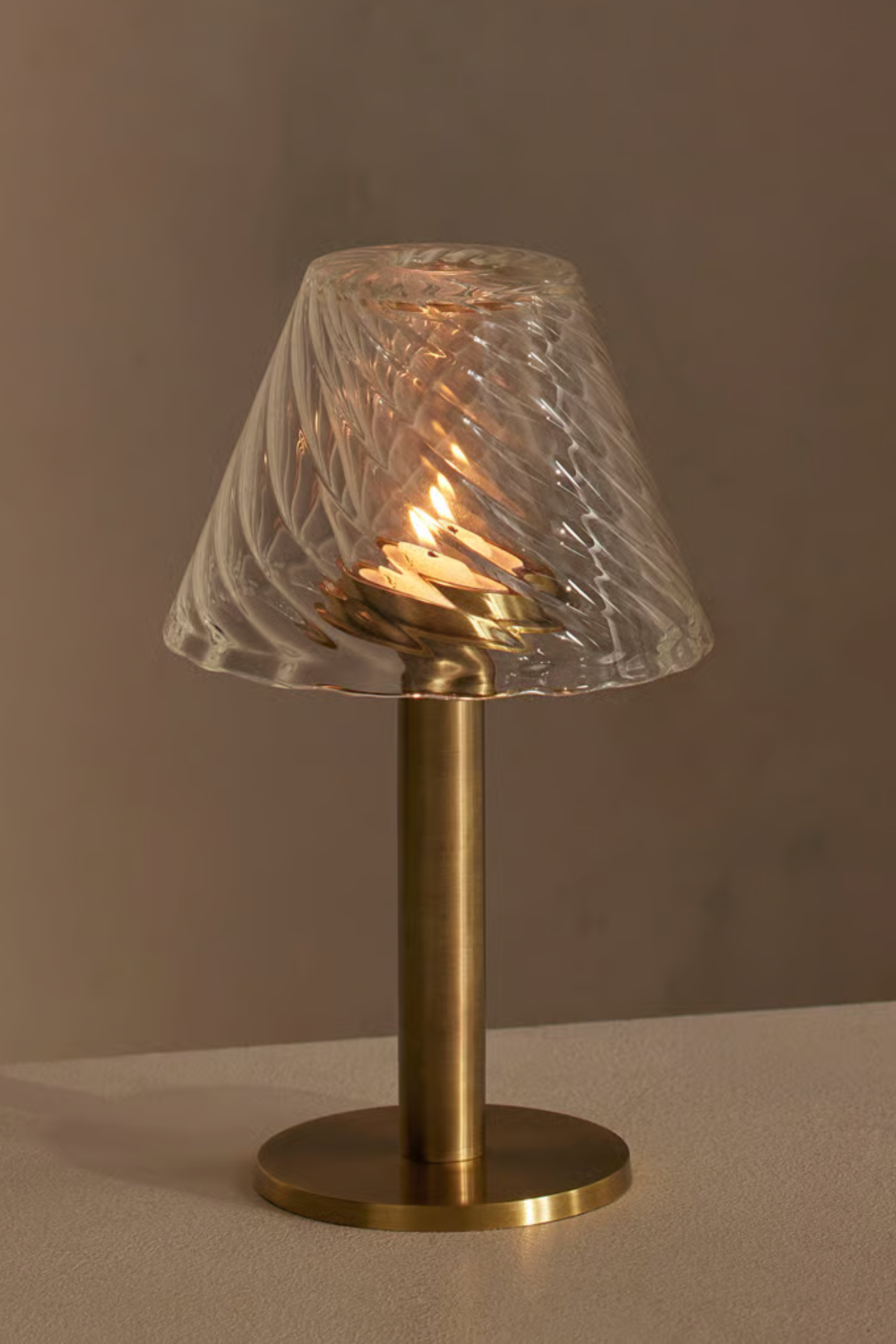 A brushed gold tealight holder with a rippled glass lamp shade