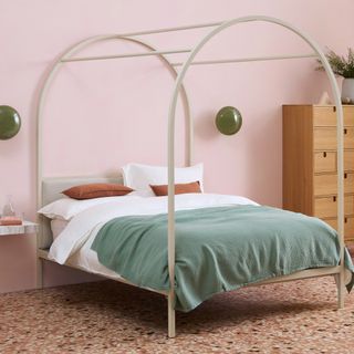 Contemporary four poster bed with white bed linen and green bedspread in a pink bedroom with terrazzo floors