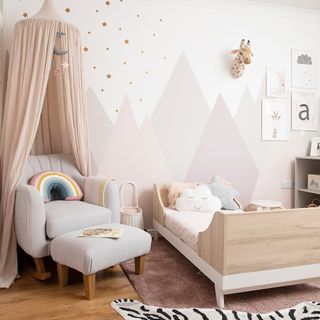 Child's bedroom with pastel pink mountains, nursing chair and canopy