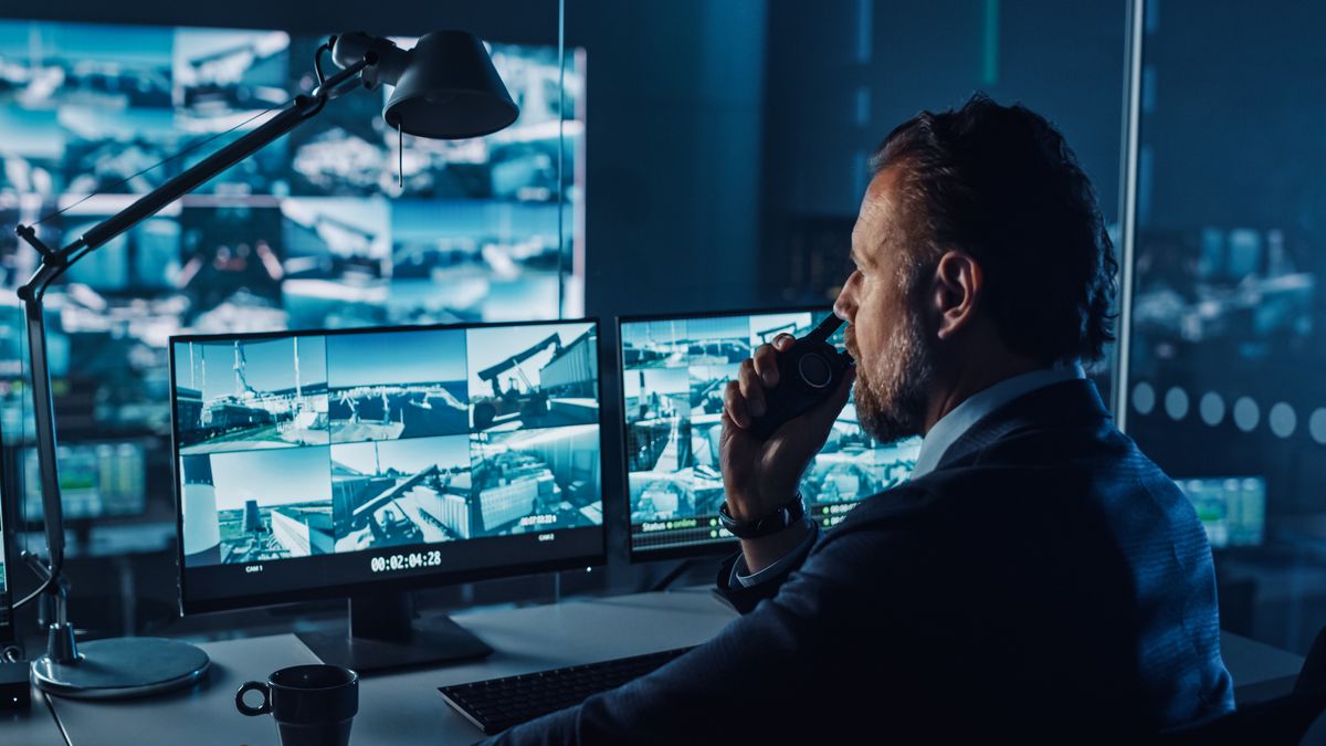 A male police officer watches a number of CCTV feeds on a computer monitor