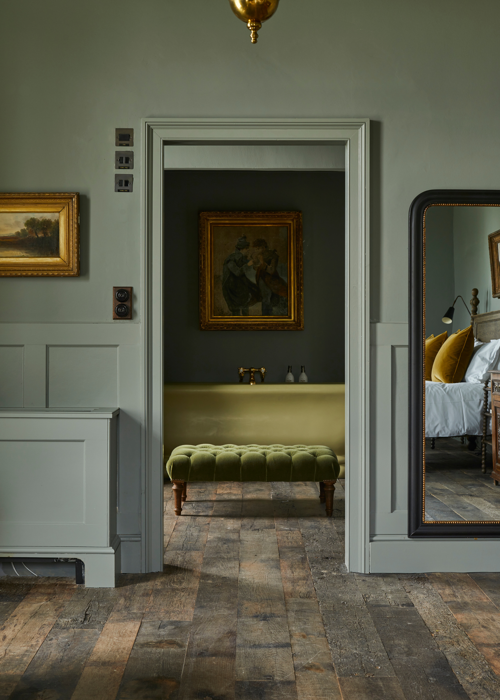 sage green bedroom with no door leading to the en suite with a freestanding green tub