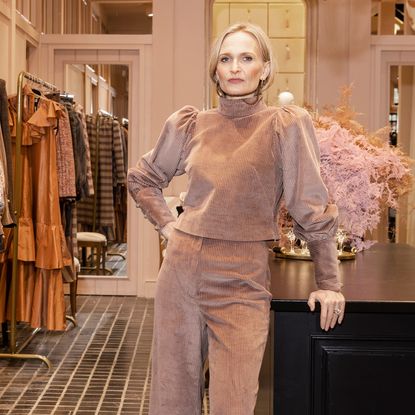 Anna Mason wearing a mauve top and pants posing in her shop