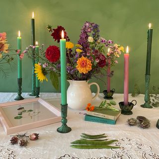 table with vase of flowers and colourful candlesticks in candle holders