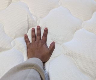 A hand resting on the Helix Plush Mattress Topper.