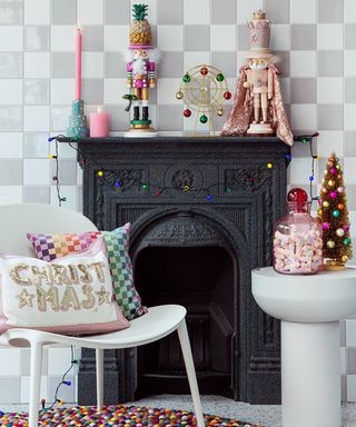 A living room with Christmas mantel including slogan cushions, nutcracker decor, glass jar with marshmallow sweets and gold tree topper