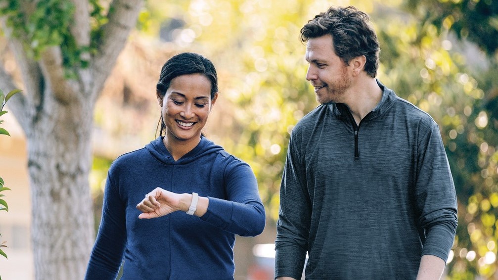 Woman wearing Fitbit Inspire 2 walking beside man