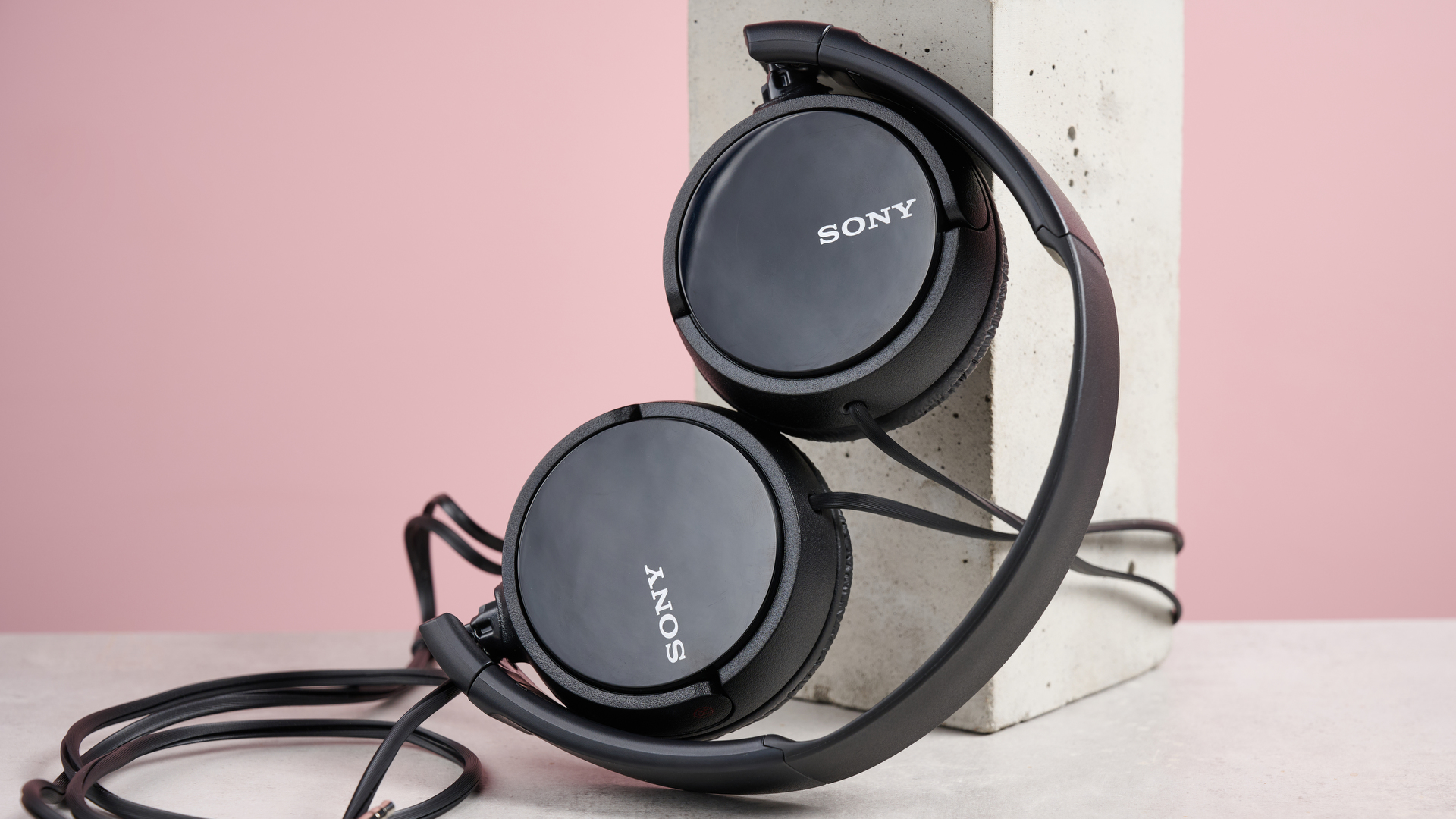 The Sony MDR-ZX110 with its earcups folded up, leaning against a pillar.