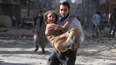 A man carries a wounded girl following a 'barrel bomb' attack in Aleppo