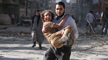 A man carries a wounded girl following a 'barrel bomb' attack in Aleppo