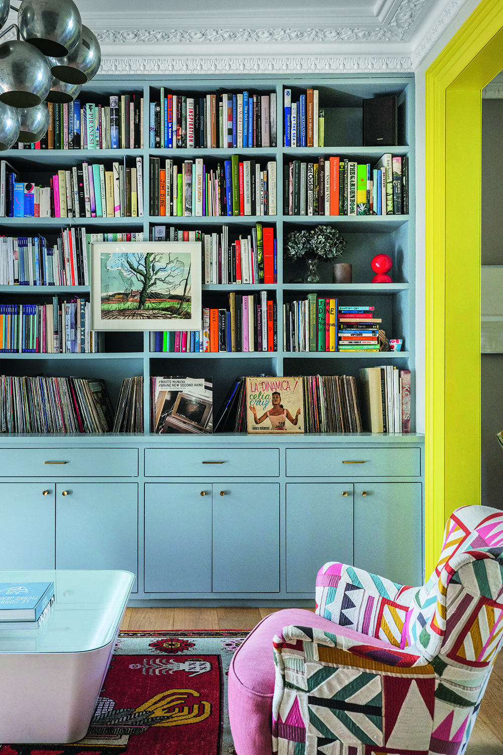 Bright narrow living room in a townhouse with shelves and a glossy green painted arch