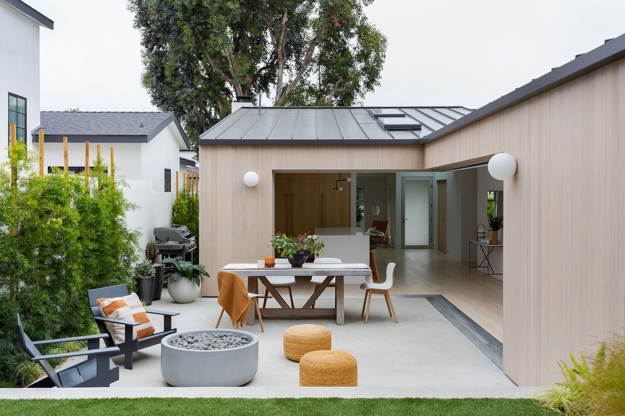 A backyard with privacy trees and shrubs against a fence