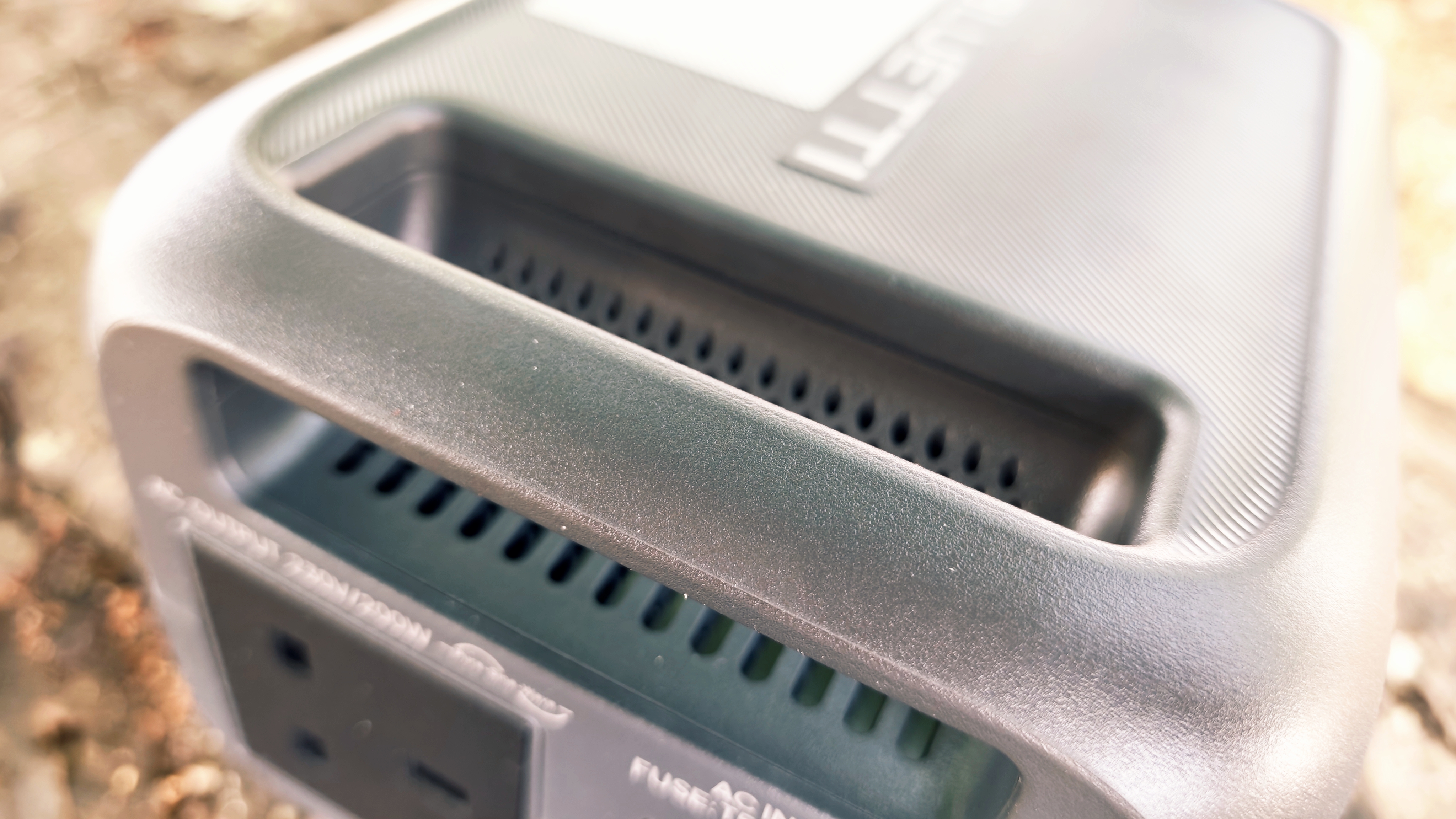 A grey Bluetti Elite 10 power station sitting on a log in a forest grove
