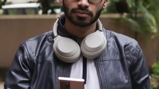 Man wearing Sony WH-1000XM4 headphones around his neck