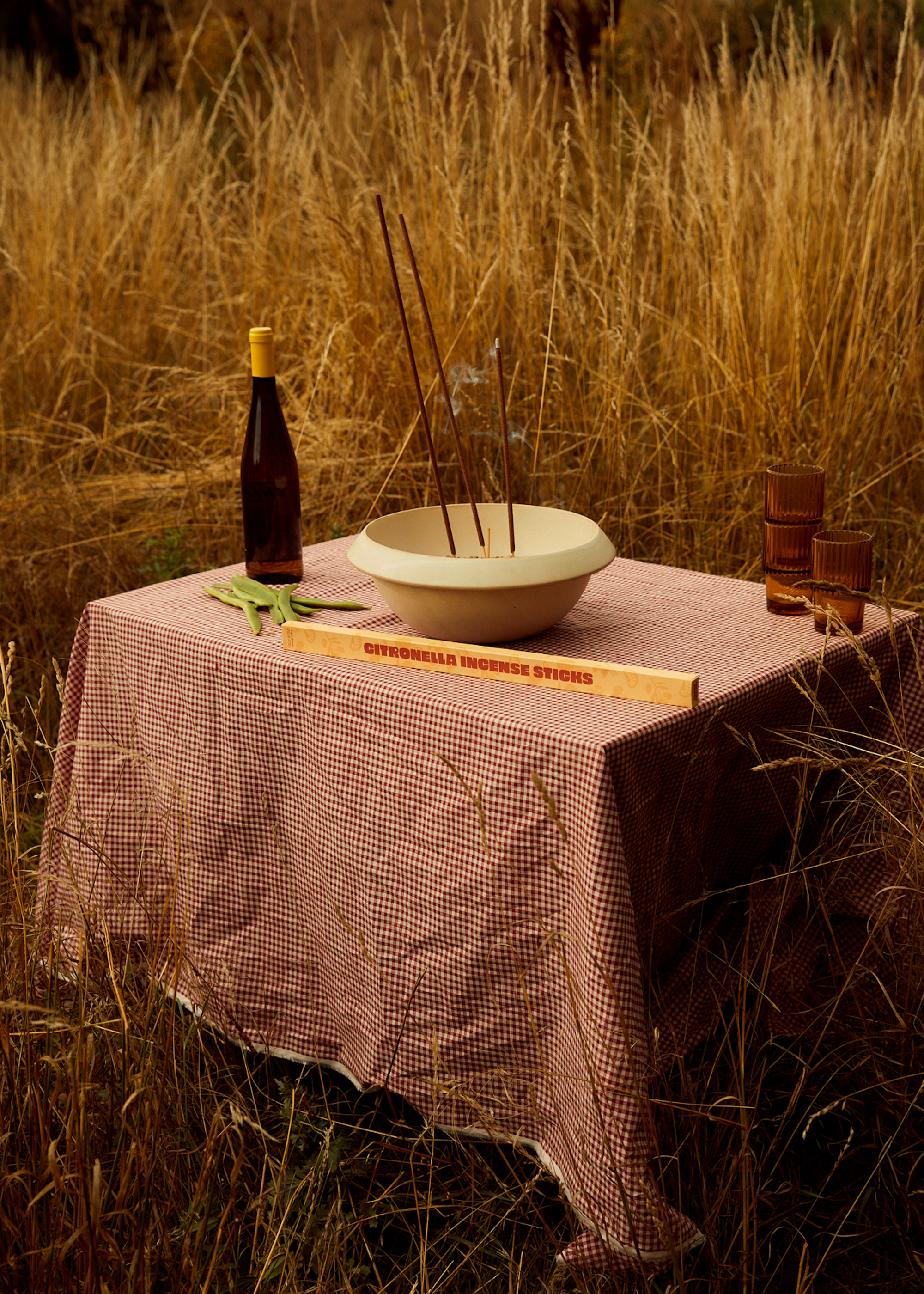 An outdoor table in an overgrown garden with a bowl of garden incense