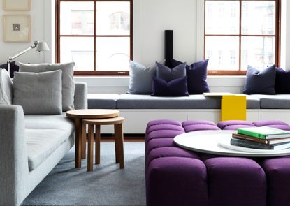 A living room with light grey sofa and purple ottoman