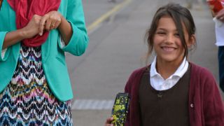 Jade Green smiling and holding a packet of sweets in her school uniform.