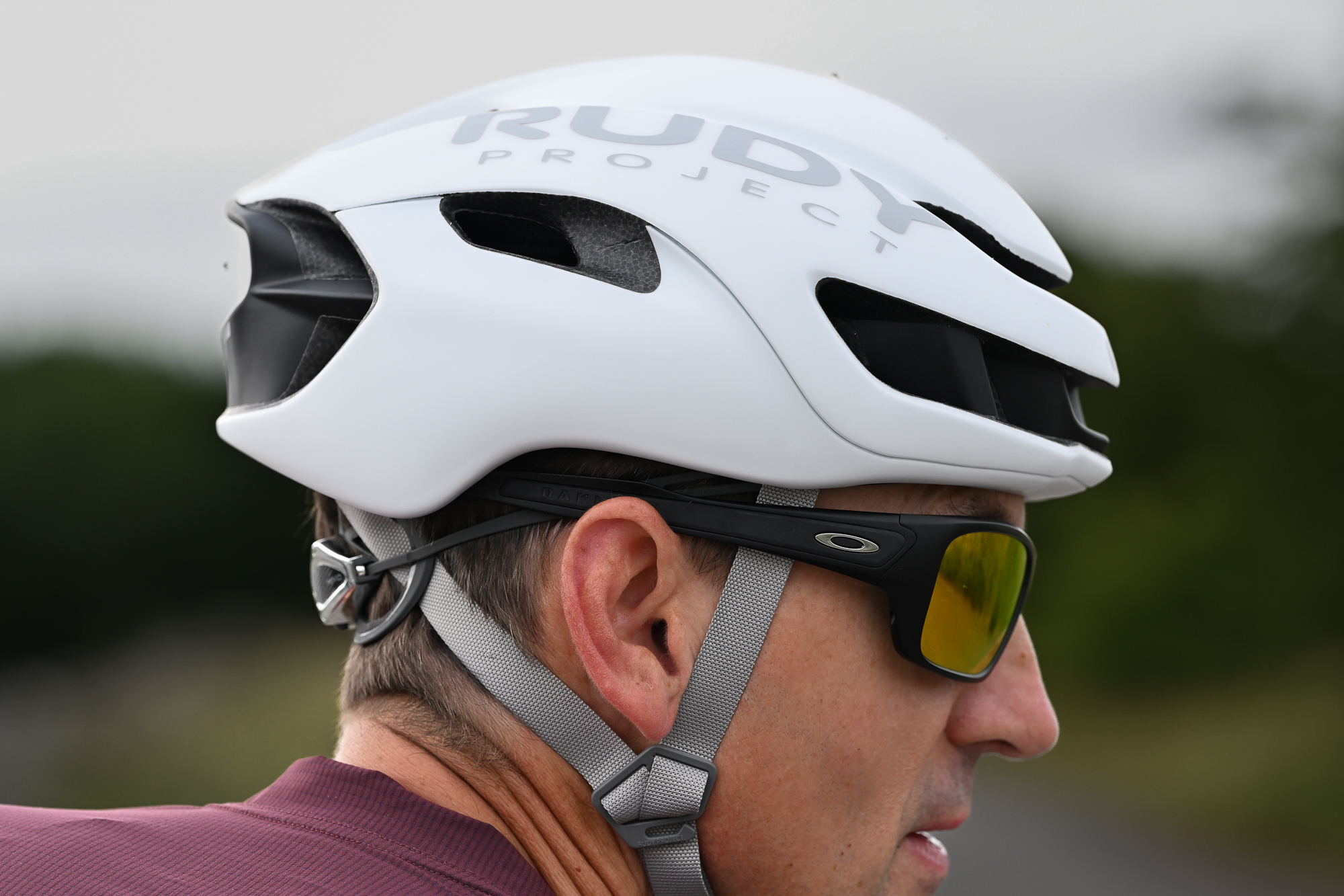 side view of a mane wearing a white helmet and purple jersey with sunglasses on