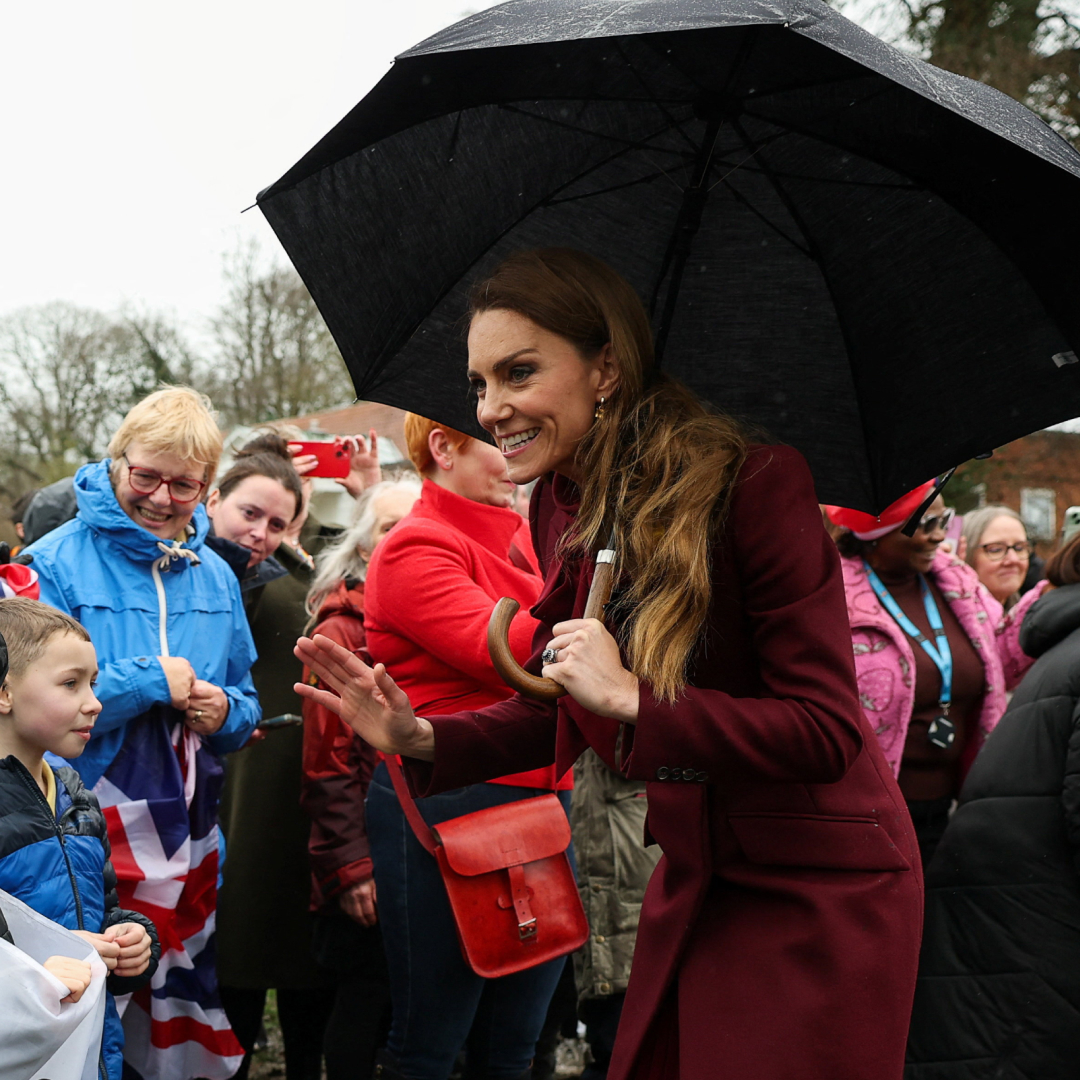 Princess Kate holding an umbrella talking to fans in the rain