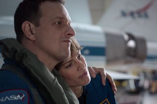 Josh Charles and Hilary Swank, as fictional astronauts Matt Logan and Emma Green, sit in front of a real NASA T-38 jets in a scene from the Netflix series "Away" filmed on location in NASA's hangar at Ellington Airport in Houston, Texas.