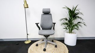 Steelcase Gesture in grey upholstery on a rug beside a floor lamp and potted plant